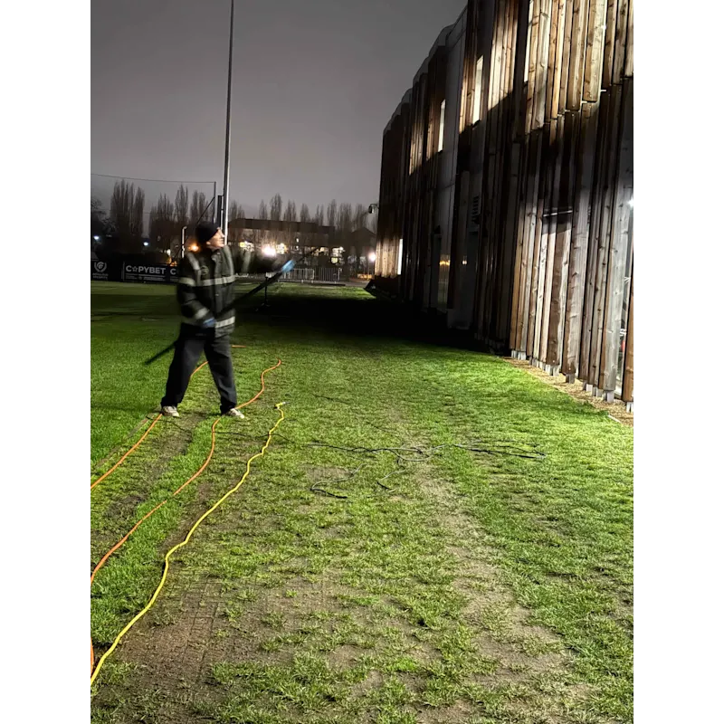Exterior cleaning work on a stadium perimeter after dark