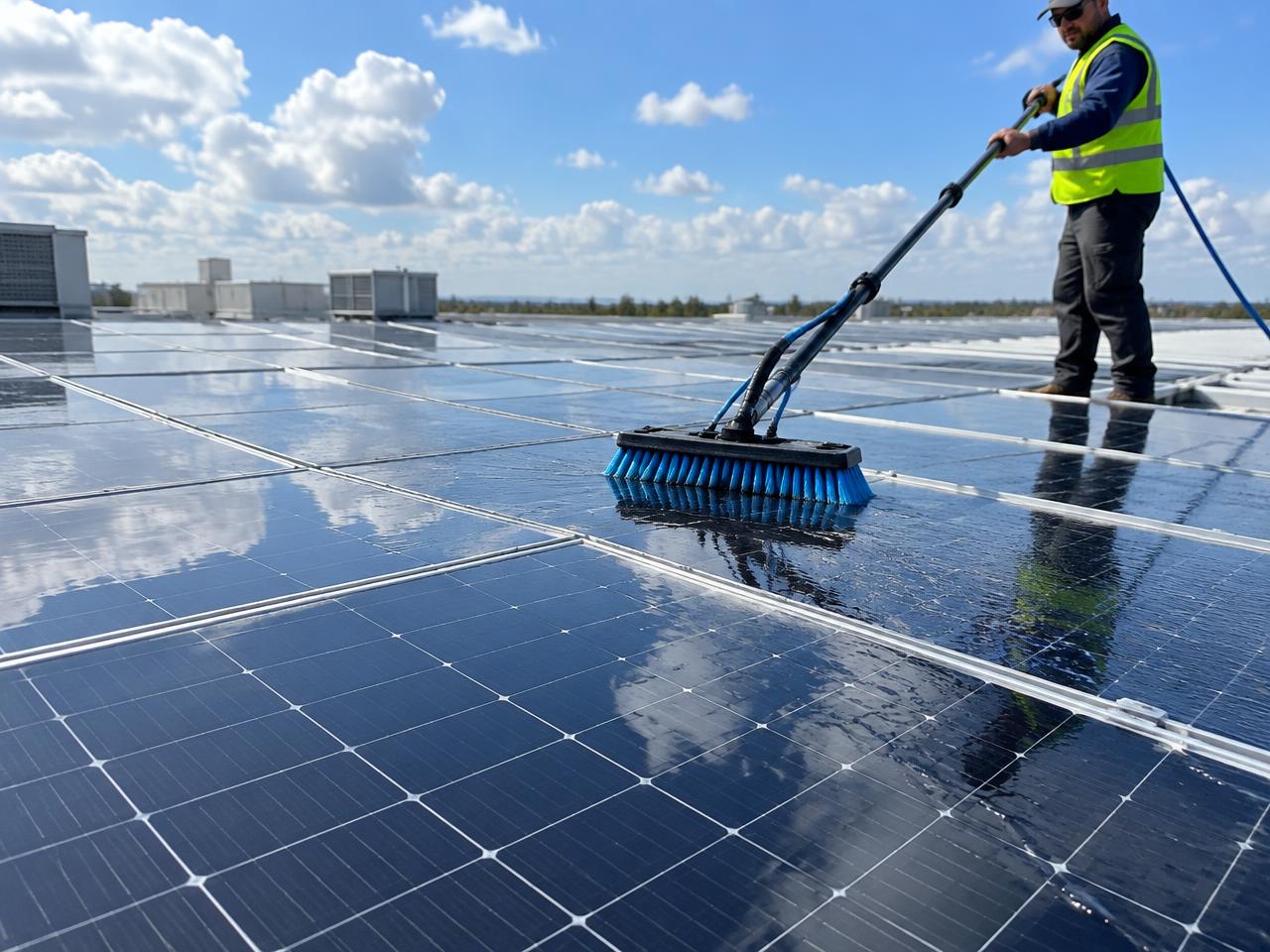 Solar panels being cleaned with a water-fed brush
